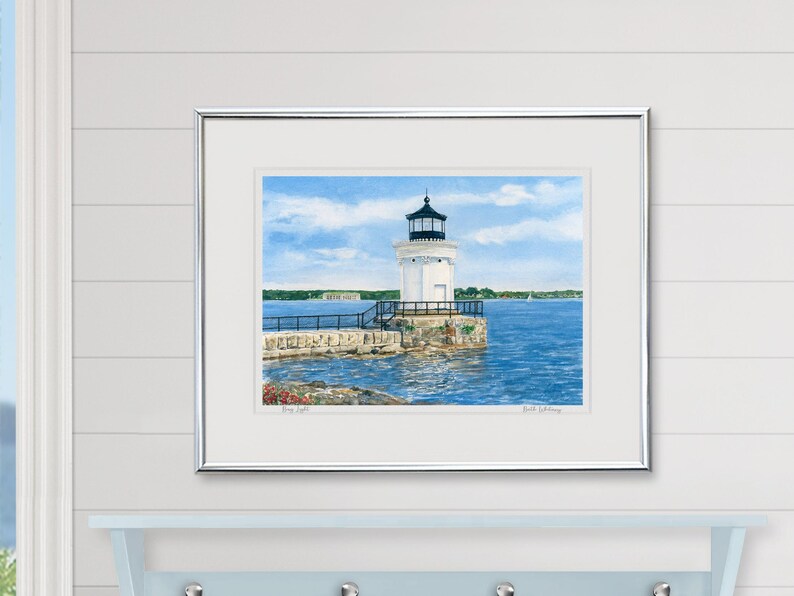 Framed watercolor art print of Bug Light displayed in a coastal-inspired room, featuring the lighthouse and Fort Gorges beyond.