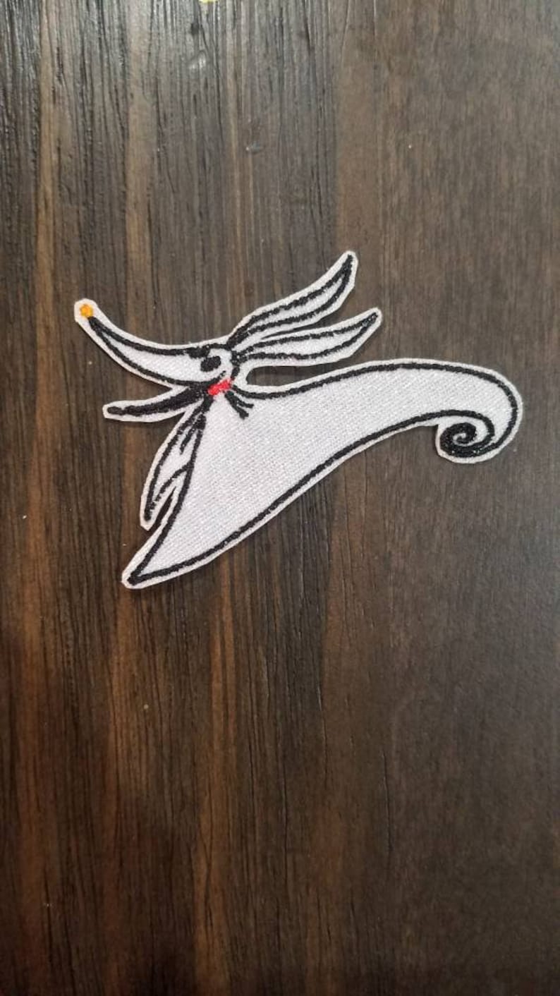 K&ouml;nnte beinhalten: Wei&szlig;er gestickter B&uuml;gel-Patch von Zero, dem Geisterhund aus Nightmare Before Christmas, mit schwarzen N&auml;hten und einem roten Mund.
