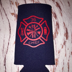 May include: A blue neoprene can cooler with a red firefighter emblem. The emblem features a fire hydrant, an axe, a ladder, a helmet, and the number 36. The words "CHIEF" are printed below the emblem.