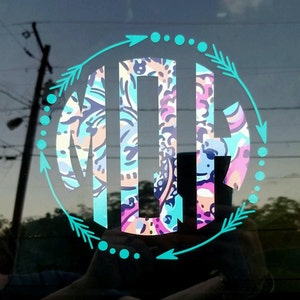 May include: A teal blue circle with a patterned monogram in the center. The circle is decorated with teal blue arrows and dots.