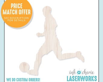 May include: A wooden silhouette of a soccer player kicking a ball. The silhouette is cut out of a light brown wood with a wood grain pattern. The text "ink cherie LASERWORKS" is in the bottom right corner of the image.