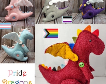 May include: Five felt plush toy dragons, each with a different color and a different pride flag on the background. The dragons are all in a sitting position with their wings spread out. The flags are: transgender, intersex, asexual, lesbian, and gay.