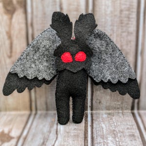 May include: Black felt moth plush toy with large red eyes and gray felt wings.