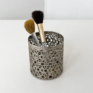 May include: A white ceramic mug with a black handle and the text "But First, Coffee" in a black, handwritten-style font. The mug is on a white surface.