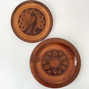 May include: A white ceramic mug with a black handle and the text "But First, Coffee" in a bold, black font. The mug is set against a blurred background, suggesting a cozy setting.