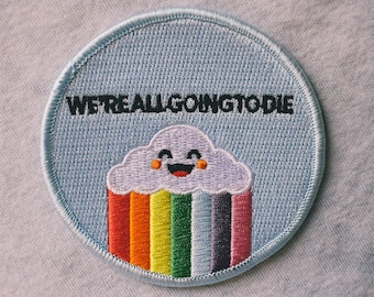May include: A blue embroidered patch with a rainbow cloud and the text "WE'RE ALL GOING TO DIE".