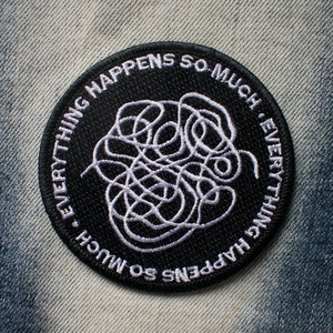 May include: Black and white embroidered patch with the text "Everything happens so much. Everything happens so much."  The text is in a circle around a white tangled line design.