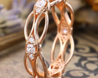 May include: Rose gold ring with an openwork design. The ring features a series of oval shapes connected by delicate bars. Small, clear gemstones are set at intervals along the ring's surface, adding sparkle.
