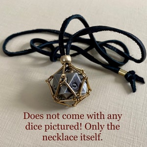 May include: A black leather cord necklace with a gold metal cage pendant. The cage is designed to hold a dice, but the dice is not included.