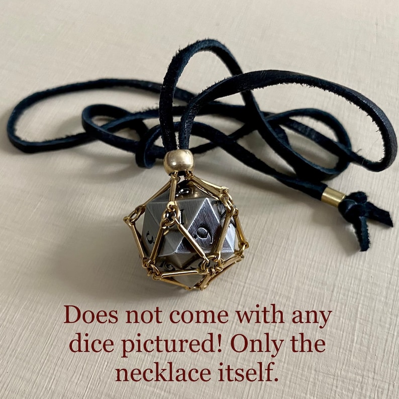 May include: A black leather cord necklace with a gold metal cage pendant. The cage is designed to hold a dice, but the dice is not included.