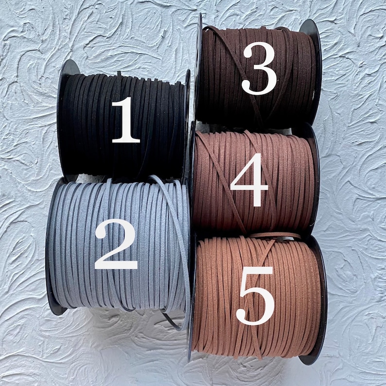 May include: Five spools of suede cord in different colors. The spools are labeled 1 through 5. The colors are black, gray, brown, dark brown, and light brown.
