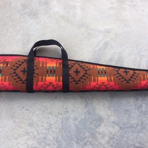 May include: A brown and red patterned gun case with a black handle and the name "Presley" embroidered on the front.