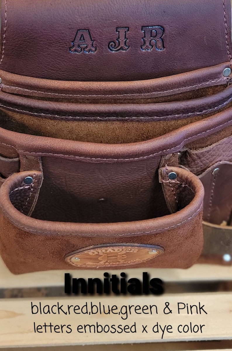 May include: Close-up of a brown leather tool belt with embossed initials "AJR" at the top. The belt has multiple pockets and a suede-lined pouch. The text "Innitials" and color options are visible.