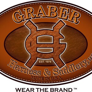 May include: A brown oval logo with the text "GRABER" in orange, and "Harness & Saddlery, LLC" in white. The logo includes the text "EST. 1974" and "MADE IN U.S.A." in white. The words "WEAR THE BRAND" are at the bottom.