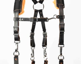 May include: Black leather camera straps with sheepskin padding. The straps have adjustable buckles and metal clips.