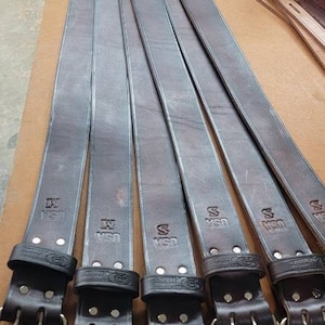 May include: Six brown leather belts with silver buckles. Each belt has the text "USA" embossed on it.