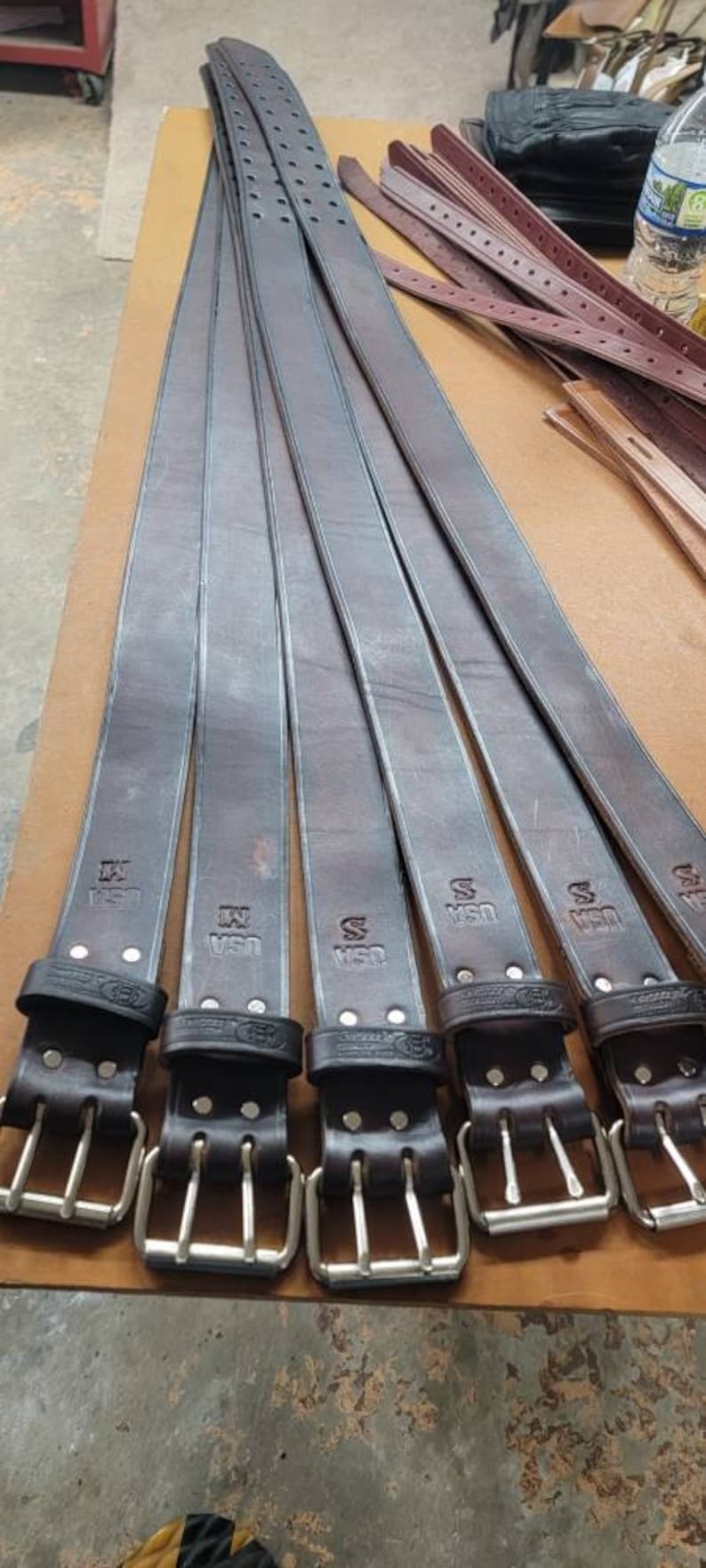 May include: Six brown leather belts with silver buckles. Each belt has the text "USA" embossed on it.