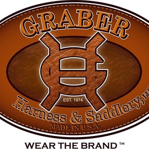 May include: A brown leather oval logo with the text "GRABER" in a white serif font. The logo also includes a stylized "G" symbol and the text "EST. 1974 Harness & Saddlery, LLC MADE IN U.S.A. WEAR THE BRAND TM".