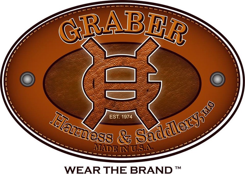 May include: A brown leather oval logo with the text "GRABER" in a white serif font. The logo also includes a stylized "G" symbol and the text "EST. 1974 Harness & Saddlery, LLC MADE IN U.S.A. WEAR THE BRAND TM".