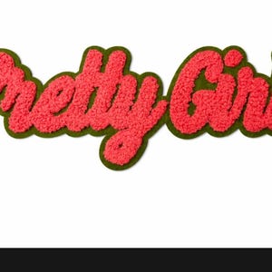 May include: A red, textured patch with the words "Pretty Girl" in a cursive font. The text is outlined with a green border. The patch is on a white background.
