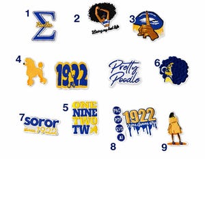 May include: A collection of embroidered patches in blue, yellow, and white. The patches feature text and graphics, including the Greek letter Sigma, a poodle, and the text "Pretty Poodle". Some patches include the year 1922.