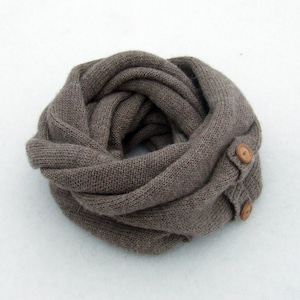 May include: A brown knitted infinity scarf with two wooden buttons.