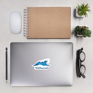 May include: A blue and white wave sticker with the text "Wildwood" on a silver laptop.