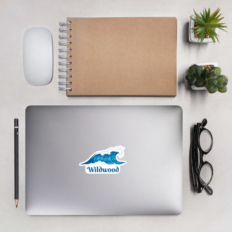 May include: A blue and white wave sticker with the text "Wildwood" on a silver laptop.