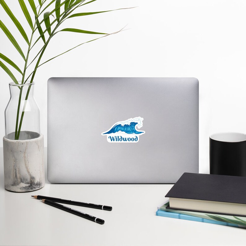 May include: A blue and white wave sticker with the text "Wildwood" on a silver laptop.