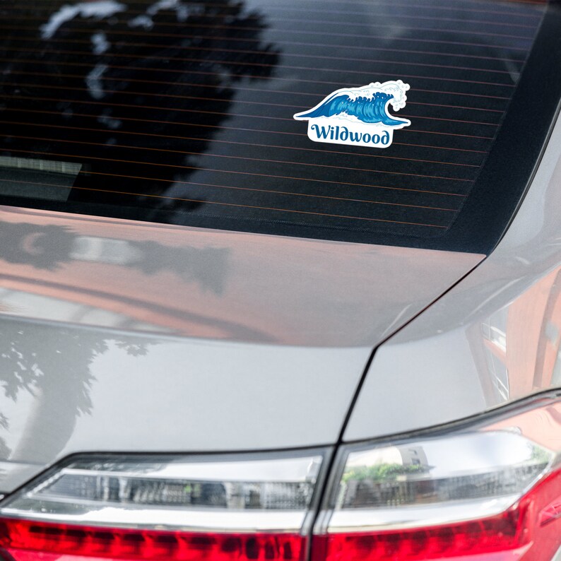 May include: A gray car with a blue and white wave sticker on the back window. The sticker says "Wildwood".
