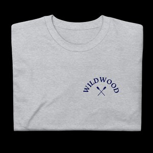 Puede incluir: Una camiseta gris jaspeada con un logotipo bordado en azul marino que dice "WILDWOOD" con dos remos cruzados.