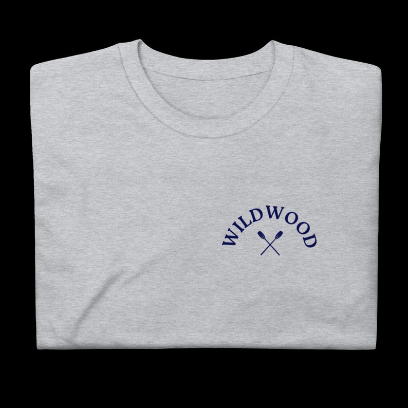Puede incluir: Una camiseta gris jaspeada con un logotipo bordado en azul marino que dice "WILDWOOD" con dos remos cruzados.