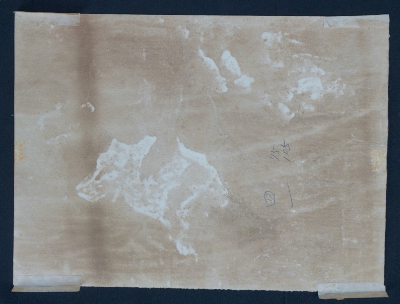 Puede incluir: Primer plano de un papel marr&oacute;n claro con manchas blancas de agua. El papel tiene los n&uacute;meros escritos a mano "115" y "103" en la esquina superior derecha.