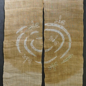 Pode incluir: Cortina de dois painéis com uma aparência natural e texturizada. O tecido transita de um bege claro no topo para um bronzeado mais escuro na parte inferior. Desenhos brancos de libélulas e redemoinhos são impressos na parte inferior. A cortina é pendurada em uma barra de madeira.