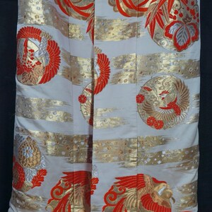 May include: A white kimono with a red and gold phoenix design. The kimono has a red trim and is made of a silky fabric.