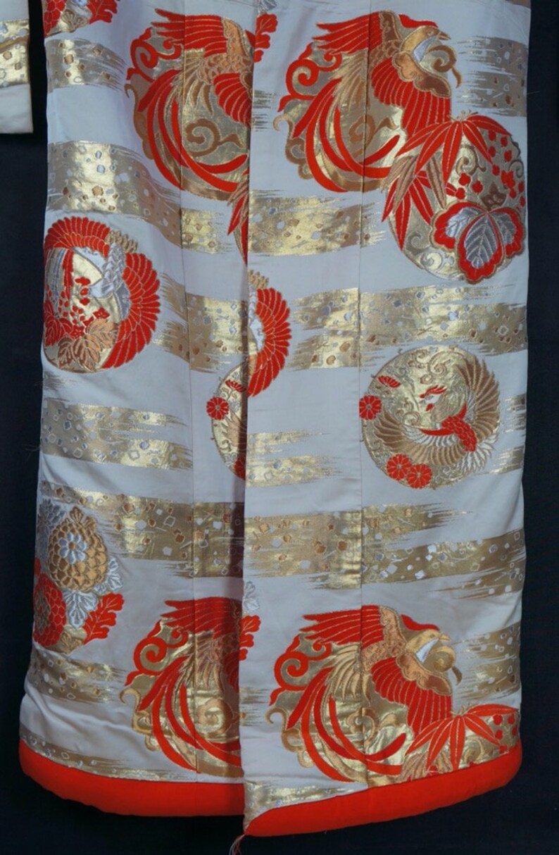 May include: A white kimono with a red and gold phoenix design. The kimono has a red trim and is made of a silky fabric.