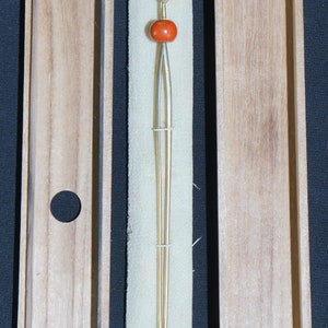 May include: A pair of gold chopsticks with a red bead at the top, in a wooden box.
