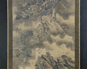 May include: A traditional Asian scroll painting depicting a dragon in a cloudy sky above mountains and water. The dragon is detailed in shades of gray and black, with a sense of movement and power. The scroll is framed in a dark brown border.
