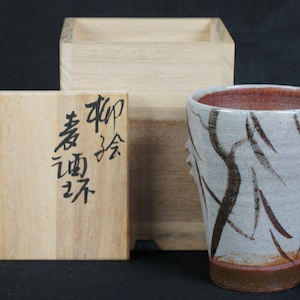 Peut inclure: Une tasse en céramique blanche avec un glaçage brun et un motif de coups de pinceau noir et blanc. La tasse est dans une boîte en bois avec des caractères japonais sur le couvercle.