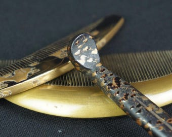 May include: A dark brown and gold patterned hair comb with a curved edge and a matching dark brown and gold textured hair pick. The comb features a smooth, metallic gold finish on the teeth and a decorative, mottled dark surface with gold accents.