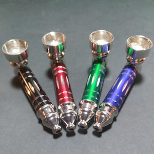 May include: Four metal pipes in black, red, green, and blue. Each pipe has a silver bowl and a colored, ridged body. The pipes are arranged diagonally, showcasing their design and color variations.