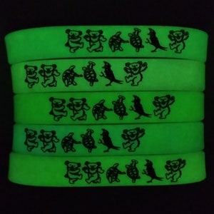 May include: A stack of green glow-in-the-dark silicone bracelets with a repeating pattern of dancing bears, turtles, and a bird.