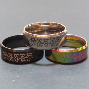 May include: Three stainless steel rings with a design of dancing bears. The rings are black, silver, and rainbow.