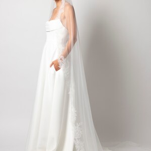 May include: A white wedding dress with a lace trim and a long white veil