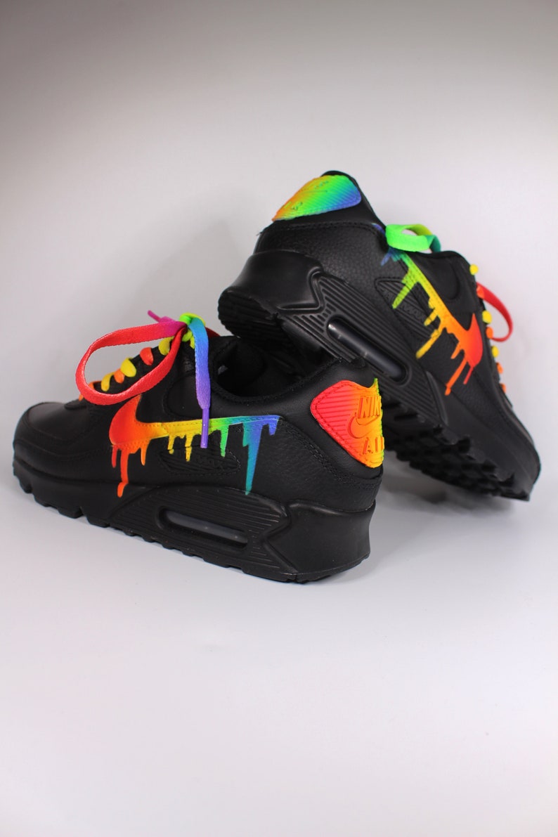 Puede incluir: Zapatillas Nike Air Max 90 negras con pintura de arco&iacute;ris goteando por los lados. Los cordones est&aacute;n atados con un esquema de colores de arco&iacute;ris.