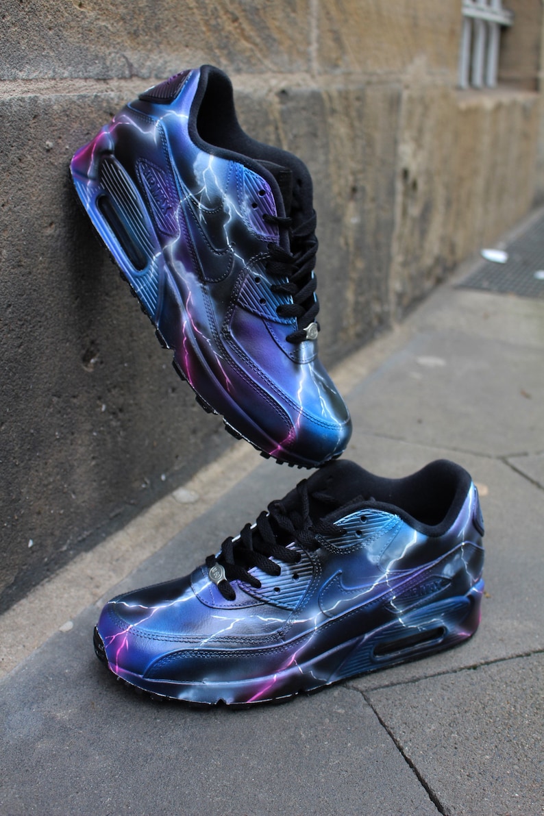 May include: A pair of black and blue sneakers with a lightning bolt design. The sneakers have a white swoosh logo and a black sole.