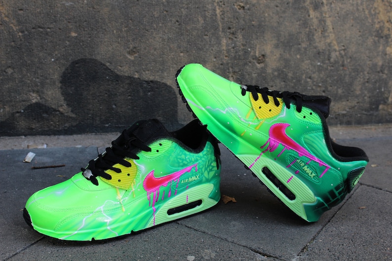 Puede incluir: Un par de zapatillas Nike Air Max verdes y negras con detalles en rosa y amarillo. Las zapatillas tienen un dise&ntilde;o de rayo y un efecto de pintura que gotea.