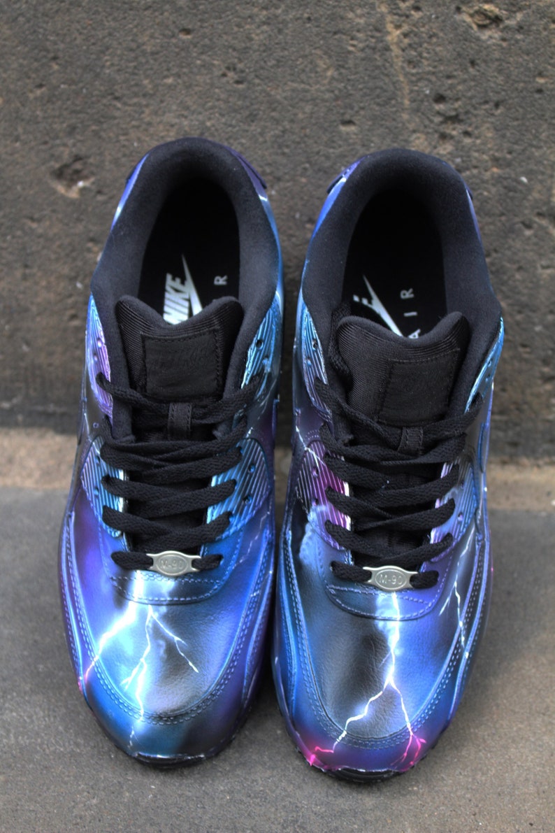 May include: A pair of black Nike Air Max 1 sneakers with a custom lightning bolt design in shades of blue, purple, and white.