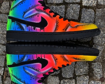 May include: A pair of black high-top sneakers with a rainbow gradient paint design. The sneakers have a black swoosh logo and black laces.