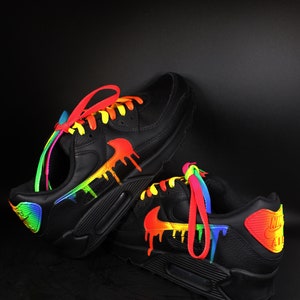 Puede incluir: Zapatillas de cuero negro con detalles de pintura de goteo arco&iacute;ris y cordones de colores.